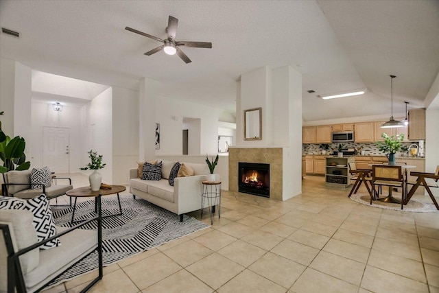 3413 Latimer Dr, Austin, TX 78732 - living area featuring lofted ceiling, light tile patterned floors, a tiled fireplace, and a ceiling fan