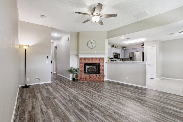 17003 Jigsaw Pathway, Round Rock, TX 78664 - unfurnished living room with ceiling fan, wood finished floors, a textured ceiling, and a fireplace