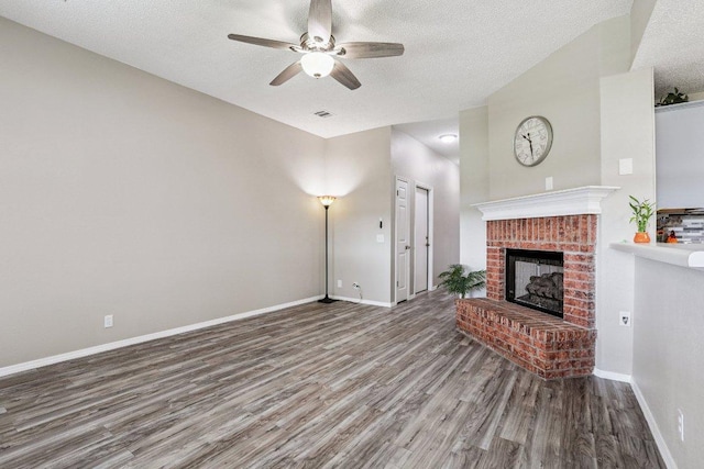 17003 Jigsaw Pathway, Round Rock, TX 78664 - unfurnished living room featuring wood finished floors, a textured ceiling, a ceiling fan, a brick fireplace, and lofted ceiling