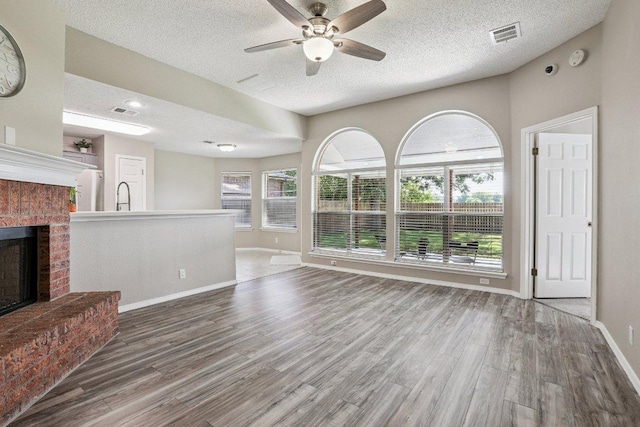 17003 Jigsaw Pathway, Round Rock, TX 78664 - unfurnished living room with a ceiling fan, wood finished floors, a textured ceiling, and a fireplace
