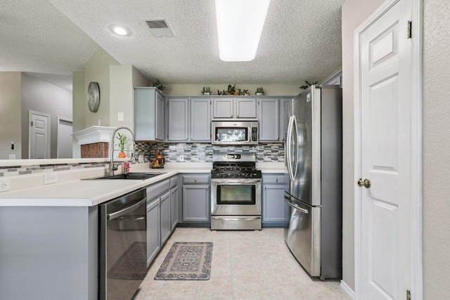 17003 Jigsaw Pathway, Round Rock, TX 78664 - kitchen with appliances with stainless steel finishes, gray cabinets, tasteful backsplash, a textured ceiling, and a peninsula