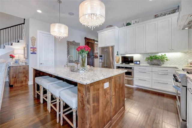 3973 River Place Blvd, Austin, TX 78730 - kitchen featuring premium appliances, extractor fan, dark wood finished floors, a kitchen island with sink, and white cabinetry