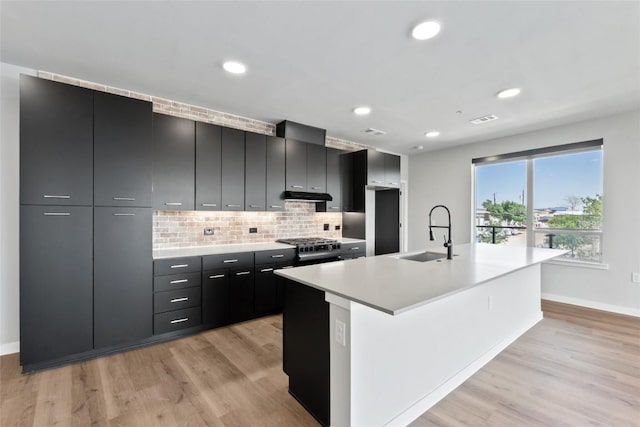 4510 Terry-O Ln Unit 230, Austin, TX 78745 - kitchen featuring dark cabinetry, light wood-style flooring, extractor fan, modern cabinets, and decorative backsplash