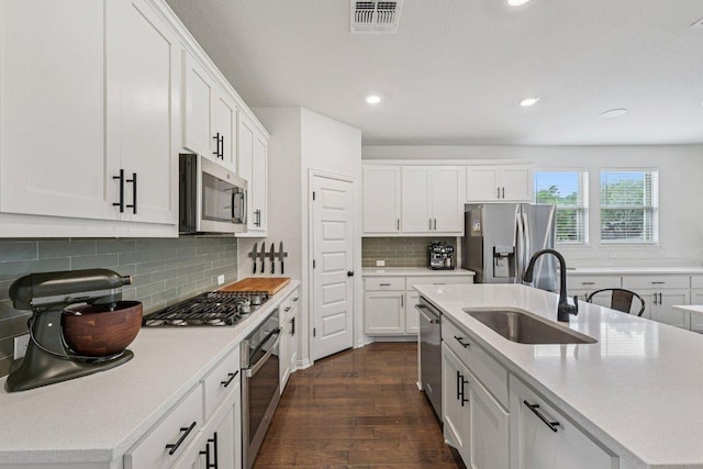 958 Pink Granite Blvd, Dripping Springs, TX 78620 - kitchen with appliances with stainless steel finishes, dark wood finished floors, a kitchen island with sink, light countertops, and white cabinetry
