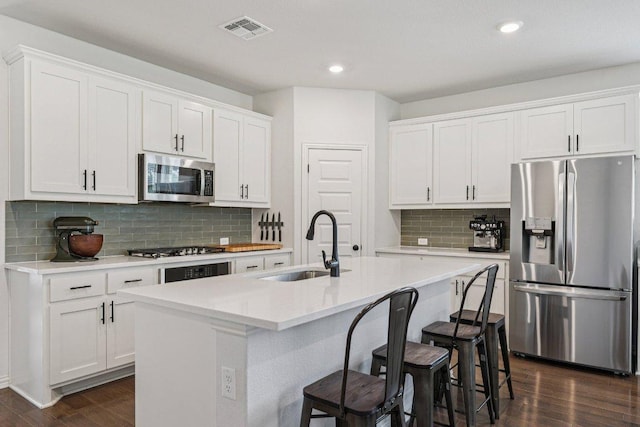 958 Pink Granite Blvd, Dripping Springs, TX 78620 - kitchen with stainless steel appliances, dark wood-type flooring, backsplash, an island with sink, and a breakfast bar