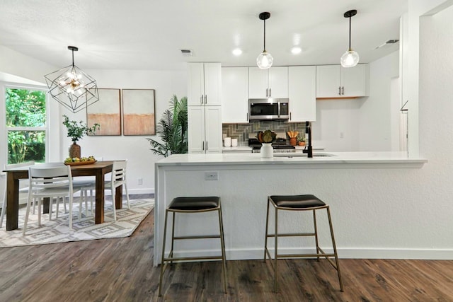 2207 Emerald Isle Dr, Leander, TX 78641 - kitchen with stainless steel microwave, decorative backsplash, dark wood-style floors, and white cabinets