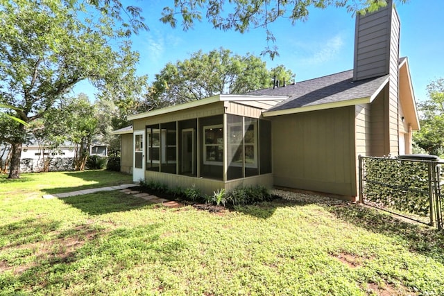 2207 Emerald Isle Dr, Leander, TX 78641 - rear view of property with a sunroom, a chimney, a yard, a shingled roof, and a garage