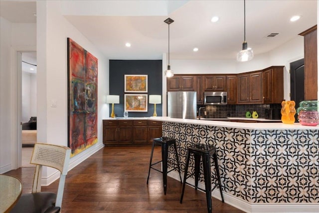 205 Versilia Cir, Lakeway, TX 78734 - kitchen featuring stainless steel appliances, light countertops, decorative backsplash, a peninsula, and dark wood-style flooring