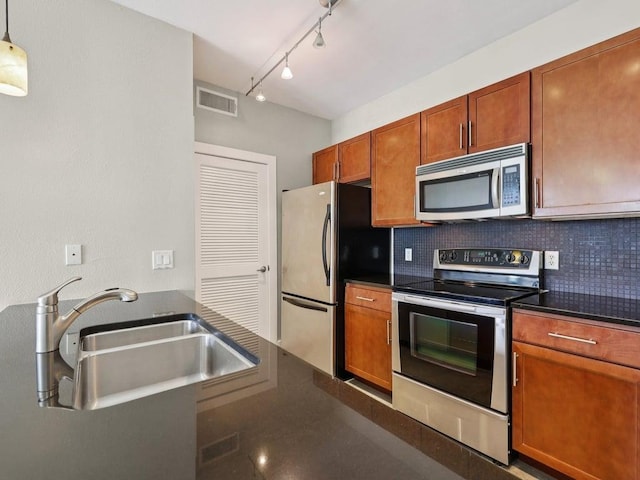 3016 Guadalupe St Unit 211, Austin, TX 78705 - kitchen with stainless steel appliances, dark countertops, decorative backsplash, rail lighting, and brown cabinetry