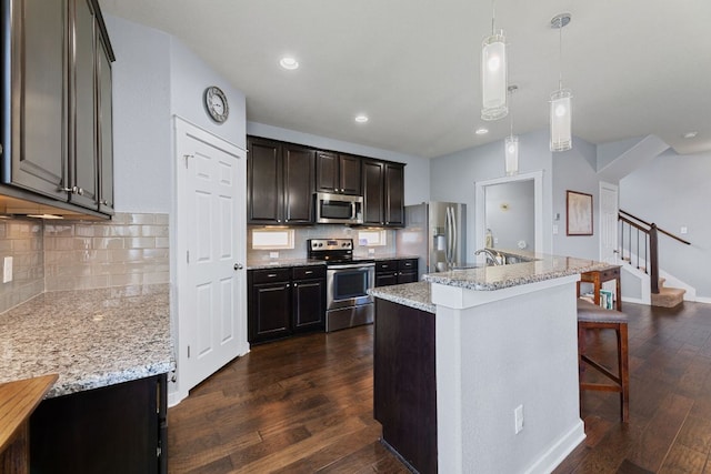 16216 Travesia Way, Austin, TX 78728 - kitchen featuring appliances with stainless steel finishes, dark wood-style flooring, a breakfast bar, tasteful backsplash, and light stone countertops