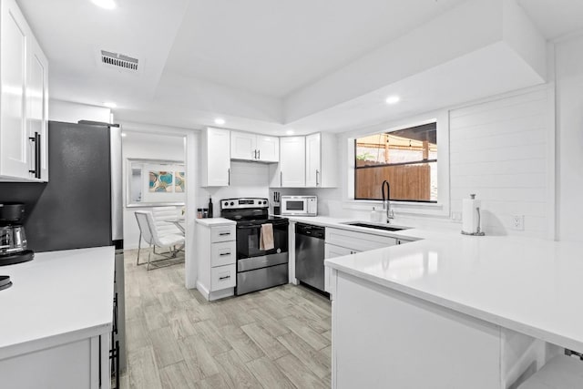 3520 Highland View Dr, Austin, TX 78731 - kitchen with stainless steel appliances, white cabinetry, a peninsula, recessed lighting, and light countertops