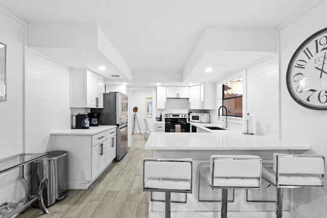 3520 Highland View Dr, Austin, TX 78731 - kitchen with stainless steel appliances, a peninsula, a breakfast bar, white cabinets, and recessed lighting