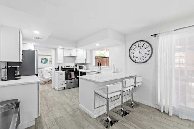 3520 Highland View Dr, Austin, TX 78731 - kitchen with appliances with stainless steel finishes, a peninsula, white cabinets, light countertops, and recessed lighting