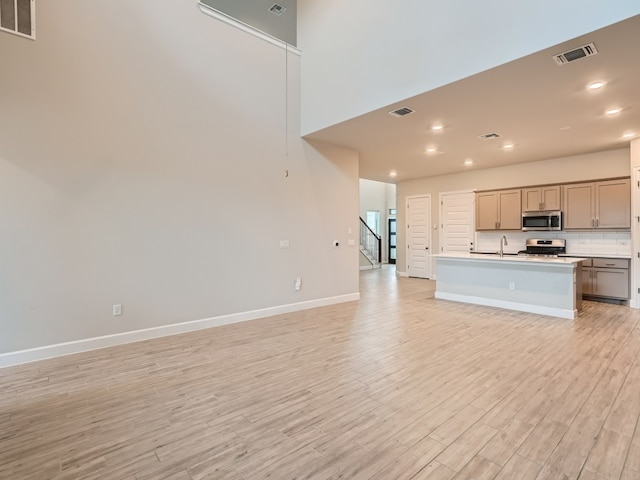 2800 Sebring Cir, Austin, TX 78747 - kitchen featuring appliances with stainless steel finishes, open floor plan, light wood-style floors, a center island with sink, and recessed lighting