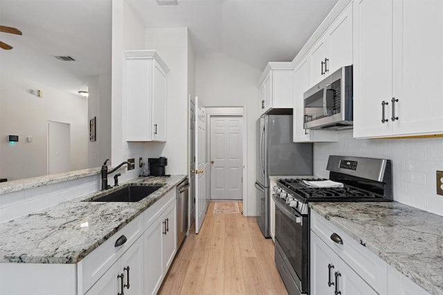 208 Meadowside Dr, Hutto, TX 78634 - kitchen featuring stainless steel appliances, tasteful backsplash, white cabinets, light wood-style floors, and a peninsula