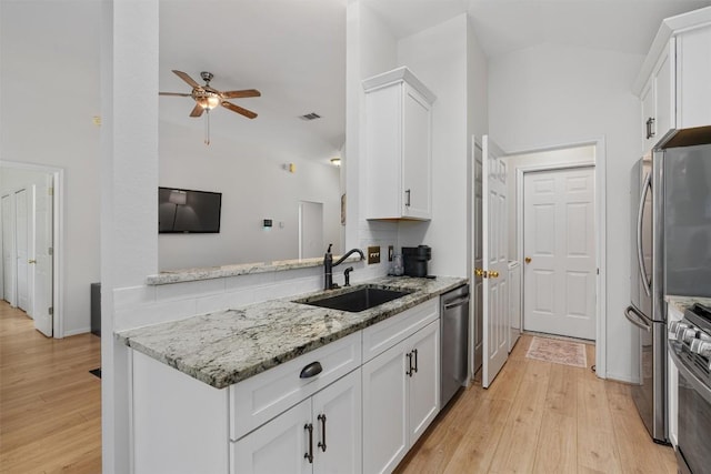 208 Meadowside Dr, Hutto, TX 78634 - kitchen with vaulted ceiling, appliances with stainless steel finishes, ceiling fan, light wood-style flooring, and white cabinets