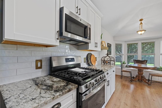 208 Meadowside Dr, Hutto, TX 78634 - kitchen featuring stainless steel appliances, vaulted ceiling, white cabinets, light stone countertops, and light wood finished floors