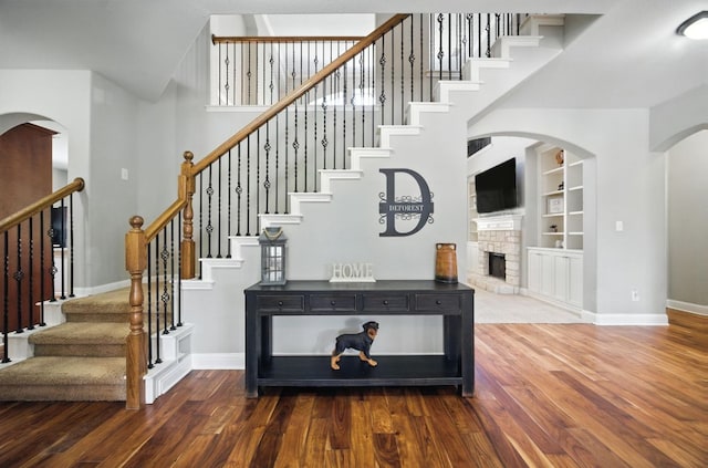 1208 Pine Forest Cir, Round Rock, TX 78665 - stairway featuring a towering ceiling, wood finished floors, arched walkways, a fireplace, and built in features
