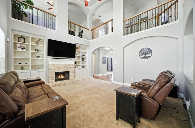 1208 Pine Forest Cir, Round Rock, TX 78665 - living area featuring ceiling fan, carpet flooring, arched walkways, a high ceiling, and a stone fireplace