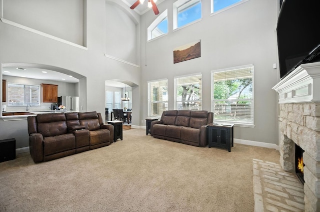 1208 Pine Forest Cir, Round Rock, TX 78665 - living area featuring arched walkways, light carpet, a fireplace, a ceiling fan, and a high ceiling