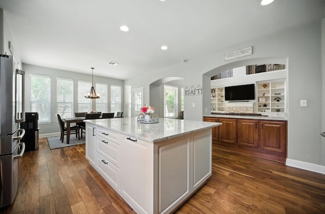 1208 Pine Forest Cir, Round Rock, TX 78665 - kitchen with arched walkways, recessed lighting, dark wood-style floors, light stone countertops, and a center island