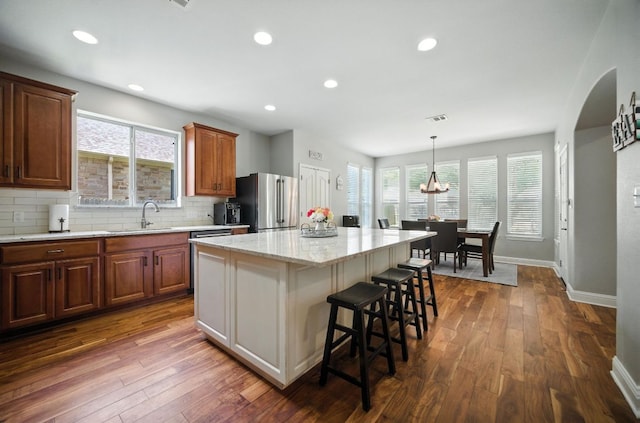 1208 Pine Forest Cir, Round Rock, TX 78665 - kitchen with freestanding refrigerator, a breakfast bar area, a center island, decorative backsplash, and dark wood-style floors