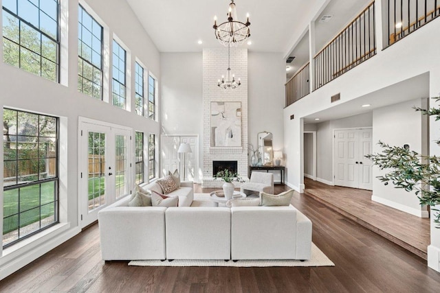 7204 Guava Cv, Austin, TX 78750 - living area featuring a towering ceiling, a chandelier, french doors, dark wood-style floors, and a brick fireplace