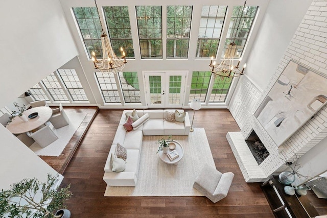 7204 Guava Cv, Austin, TX 78750 - living room with a chandelier, french doors, a high ceiling, wood finished floors, and a brick fireplace