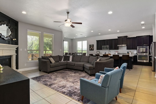 30872 Schlather Ln, Bulverde, TX 78163 - living room featuring a ceiling fan, light tile patterned flooring, a glass covered fireplace, and recessed lighting