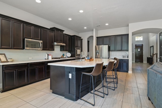 30872 Schlather Ln, Bulverde, TX 78163 - kitchen with appliances with stainless steel finishes, arched walkways, tasteful backsplash, light countertops, and an island with sink