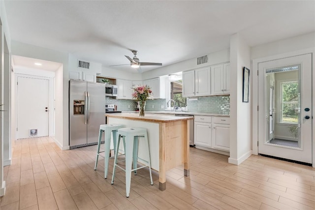 10133 Oliver Dr, Austin, TX 78737 - kitchen featuring appliances with stainless steel finishes, light countertops, white cabinetry, tasteful backsplash, and ceiling fan
