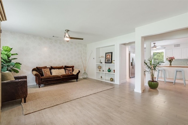10133 Oliver Dr, Austin, TX 78737 - sitting room featuring ceiling fan, an accent wall, light wood-style floors, built in features, and wallpapered walls