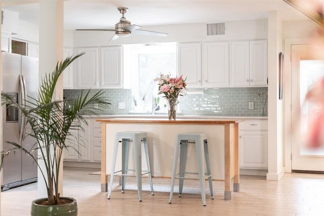 10133 Oliver Dr, Austin, TX 78737 - kitchen with stainless steel refrigerator with ice dispenser, a ceiling fan, white cabinetry, light wood finished floors, and backsplash