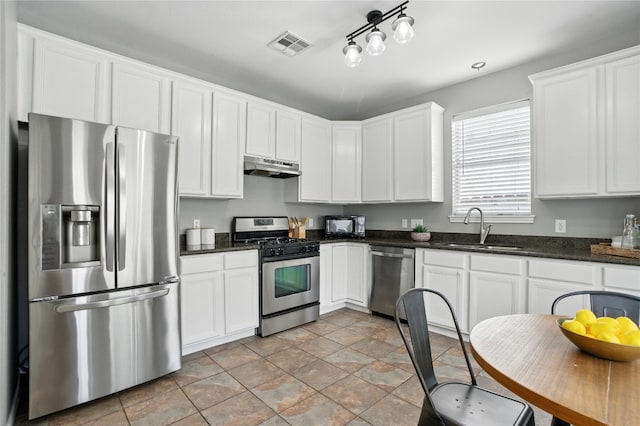 12007 Sky W Dr, Austin, TX 78758 - kitchen with stainless steel appliances, under cabinet range hood, white cabinets, light stone finish floors, and dark stone countertops