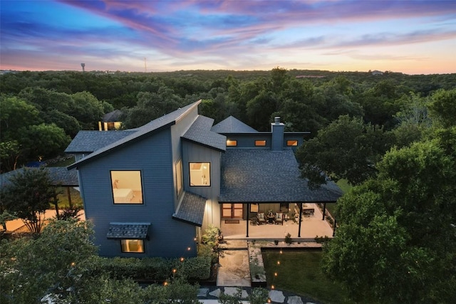 11420 Rim Rock Trl, Austin, TX 78737 - view of front of property with a chimney, a forest view, roof with shingles, and a patio area