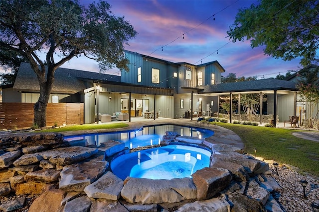 11420 Rim Rock Trl, Austin, TX 78737 - back of house at dusk with a pool with connected hot tub, a patio, and board and batten siding