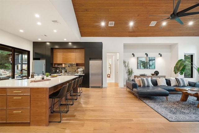 11420 Rim Rock Trl, Austin, TX 78737 - kitchen featuring stainless steel refrigerator, modern cabinets, a breakfast bar, light countertops, and light wood-style flooring