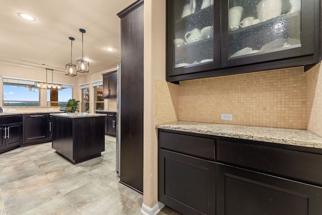 12417 Mediterra Pl, Austin, TX 78732 - kitchen featuring decorative backsplash, glass insert cabinets, light stone counters, decorative light fixtures, and recessed lighting