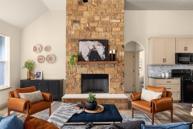 417 S Blanco St, Lockhart, TX 78644 - living room with a stone fireplace, lofted ceiling, wood finished floors, and arched walkways