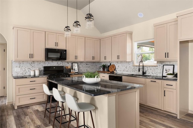 417 S Blanco St, Lockhart, TX 78644 - kitchen with black appliances, dark wood-type flooring, a center island, a kitchen bar, and lofted ceiling