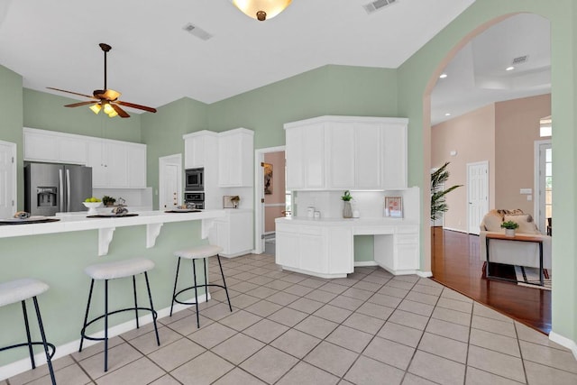 207 Golf Crest Ln, Lakeway, TX 78734 - kitchen with appliances with stainless steel finishes, a kitchen bar, a ceiling fan, white cabinetry, and a high ceiling