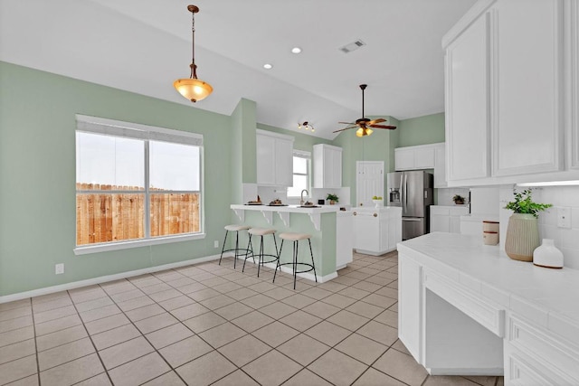 207 Golf Crest Ln, Lakeway, TX 78734 - kitchen with stainless steel fridge with ice dispenser, a kitchen breakfast bar, lofted ceiling, white cabinets, and a peninsula