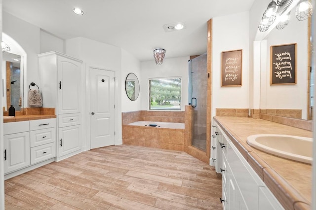 9 Heatherbloom Ln, The Hills, TX 78738 - full bath with vanity, wood finished floors, a garden tub, a shower stall, and recessed lighting