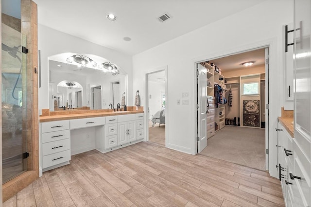 9 Heatherbloom Ln, The Hills, TX 78738 - ensuite bathroom with vanity, wood finished floors, a walk in closet, a stall shower, and recessed lighting