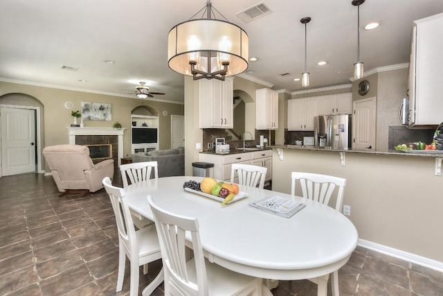 1108 Ritter Dr, Cedar Park, TX 78613 - dining room featuring a ceiling fan, ornamental molding, a tiled fireplace, arched walkways, and recessed lighting