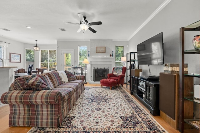 7900 Monona Ave, Austin, TX 78717 - living room featuring light wood finished floors, healthy amount of natural light, ceiling fan, crown molding, and a brick fireplace