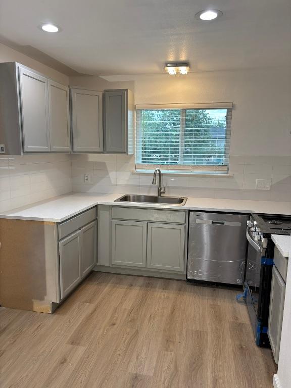 4608 E Village Ct, Austin, TX 78744 - kitchen with stainless steel appliances, gray cabinetry, backsplash, light wood-style floors, and recessed lighting