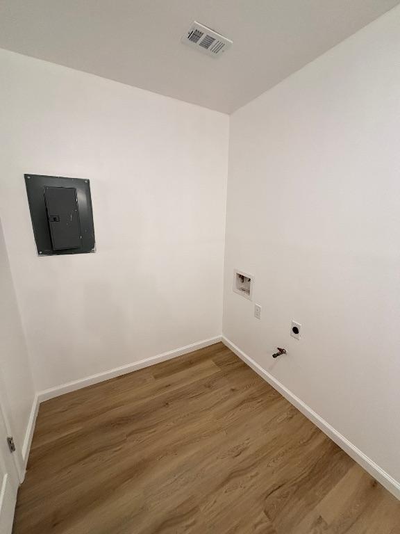 4608 E Village Ct, Austin, TX 78744 - laundry room featuring electric panel, hookup for a gas dryer, wood finished floors, hookup for a washing machine, and electric dryer hookup