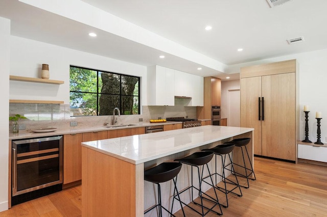 2517 Great Oaks Pkwy, Austin, TX 78756 - kitchen with wine cooler, modern cabinets, a breakfast bar, tasteful backsplash, and recessed lighting