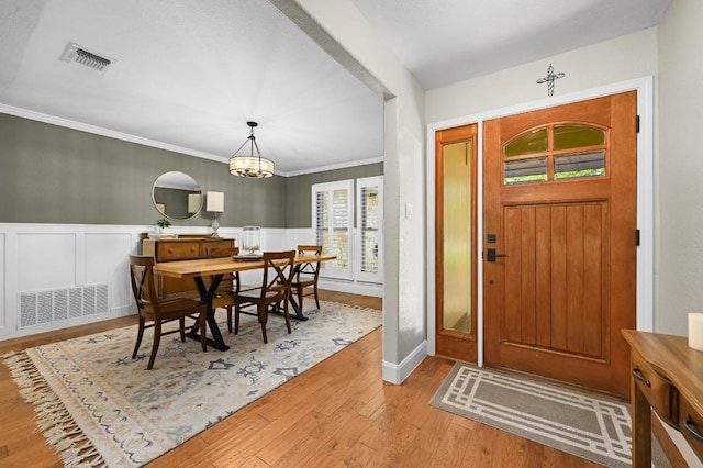 2400 Muirfield Cir, Austin, TX 78747 - foyer featuring wood-type flooring, ornamental molding, wainscoting, and a chandelier